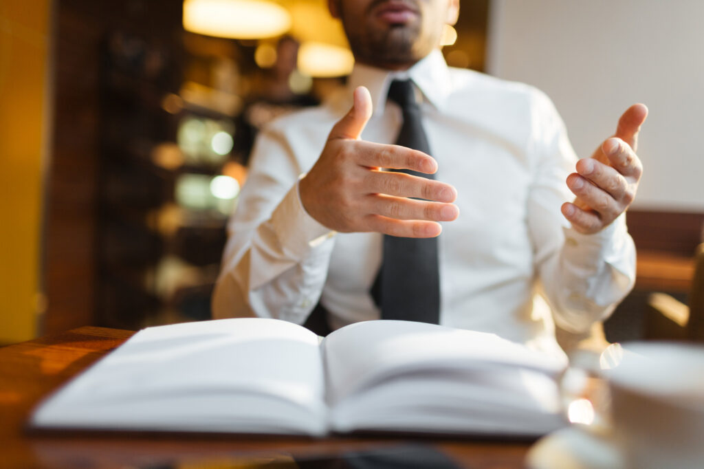 Business professional gesturing while speaking at table
